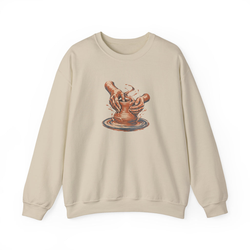 Sand Gildan 18000 crewneck sweatshirt with cupped hands shaping clay on a pottery wheel, worn screenprint-style graphic